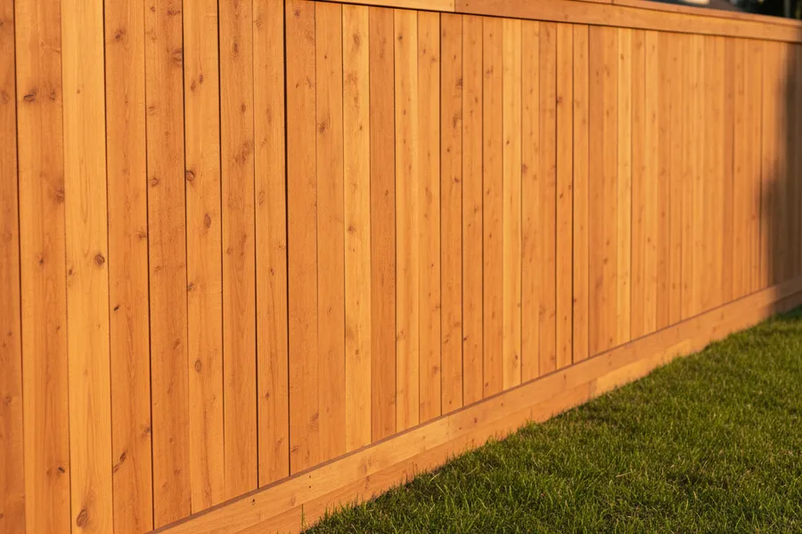 A finished board-on-board cedar fence with a top cap running straight along a property line